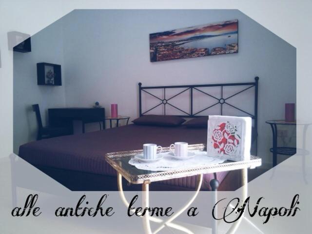 una habitación con una cama y una mesa con tazas. en Alle Antiche Terme en Nápoles