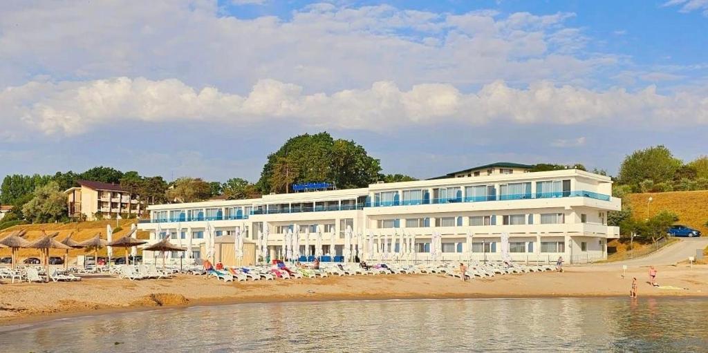 Meduza Hotel في أوليمب: مبنى ابيض كبير على شاطئ بجانب الماء