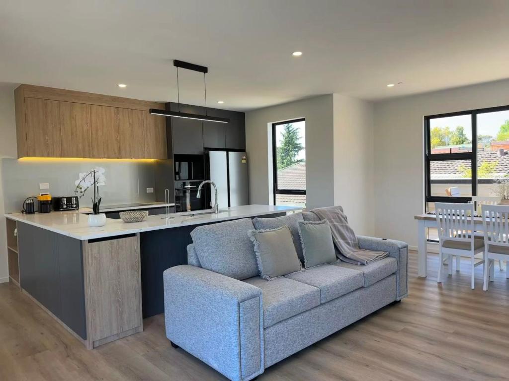 a living room with a couch and a kitchen at Northshore Charming 4 bedrooms in Auckland