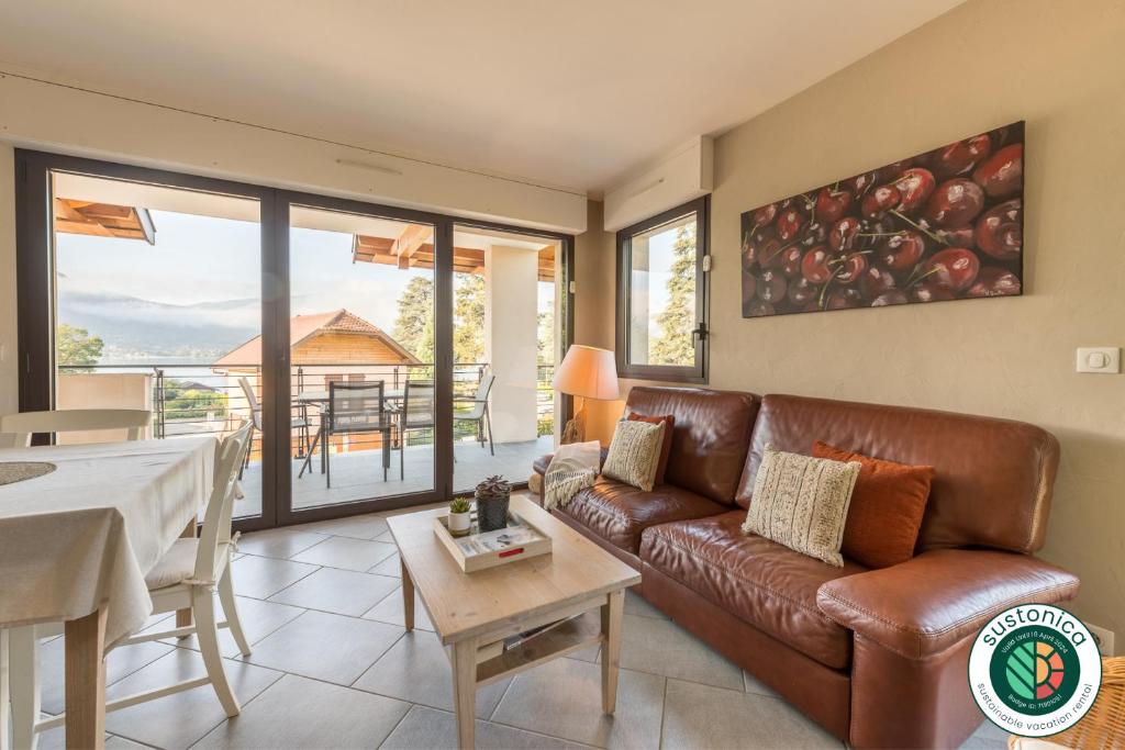 un soggiorno con divano in pelle marrone e tavolo di Le Port-Plage residence facing Talloires Beach, LLA Selections by Location lac Annecy a Talloires