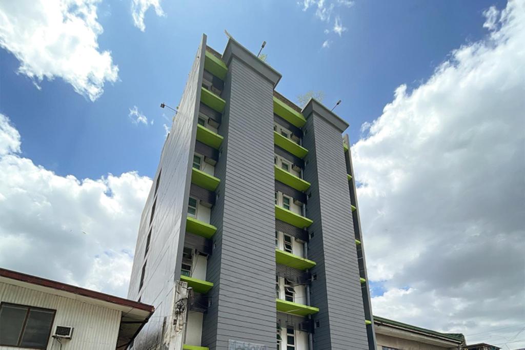un alto edificio con balconi verdi sul lato di H Plus Hotel powered by Cocotel a Manila