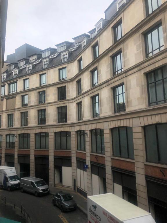 Chambre Paris في باريس: مبنى كبير فيه سيارات تقف امامه