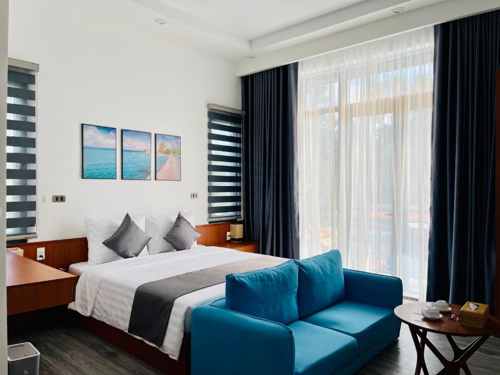 a hotel room with a bed and a blue couch at Khem Beach serviced apartment in Phú Quốc
