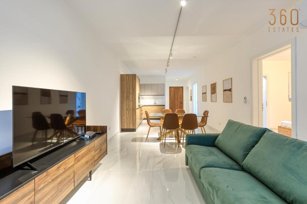 een woonkamer met een groene bank en een eetkamer bij Modern 2BR Apt with Private Terrace & Sofa Bed by 360 Estates in St Paul's Bay