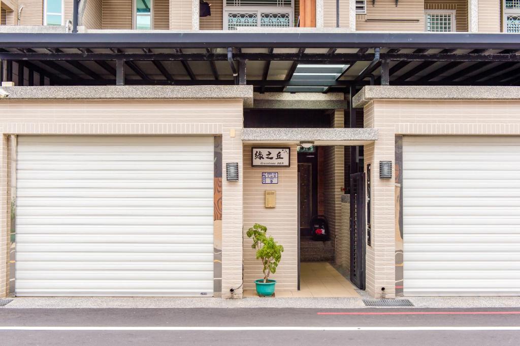 two white garage doors on a house with a plant at 綠之丘 l 寵物友善 in Taitung City