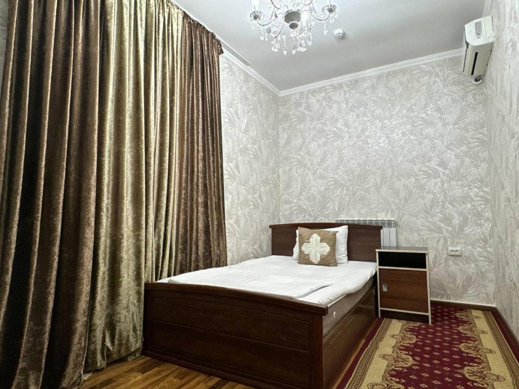 a small bedroom with a bed and a chandelier at RATMINA HOTEL in Nukus