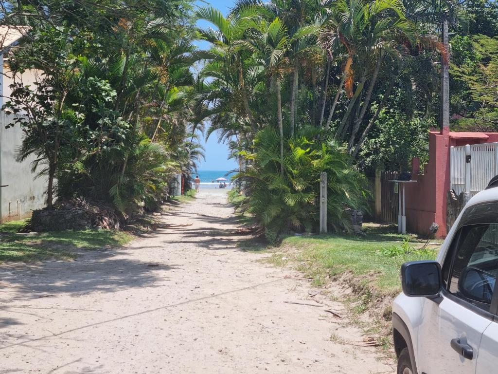 un camino de tierra con palmeras y el océano en Bela's Suítes- 60 m da praia de Barequeçaba, en Barequeçaba