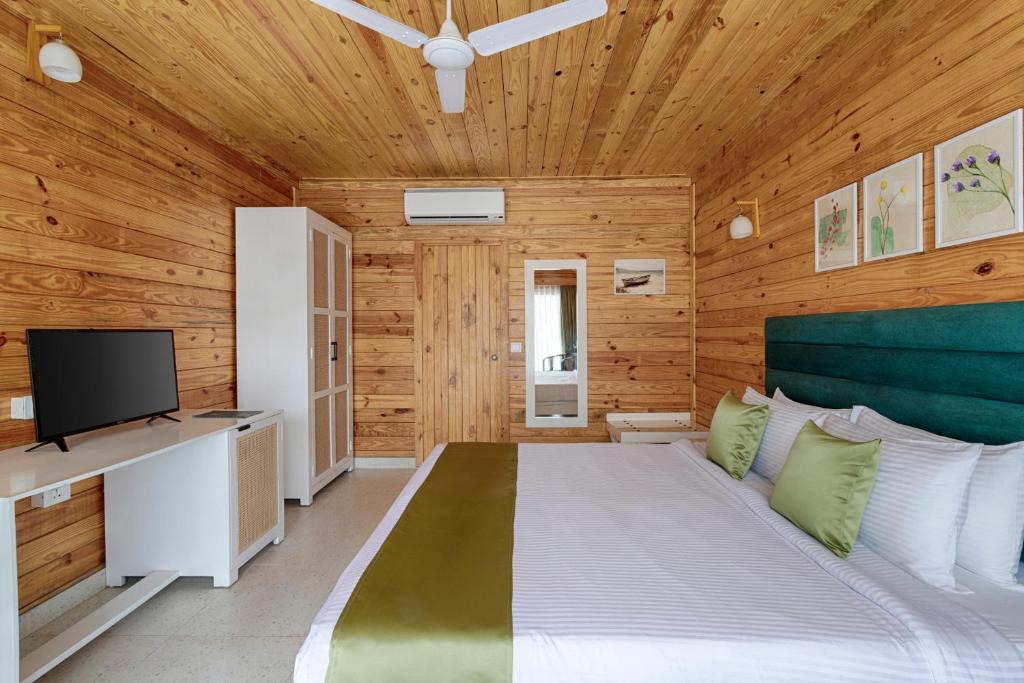 a bedroom with wooden walls and a bed with a television at Aralea Beach Resort By Stone Wood, Morjim in Morjim