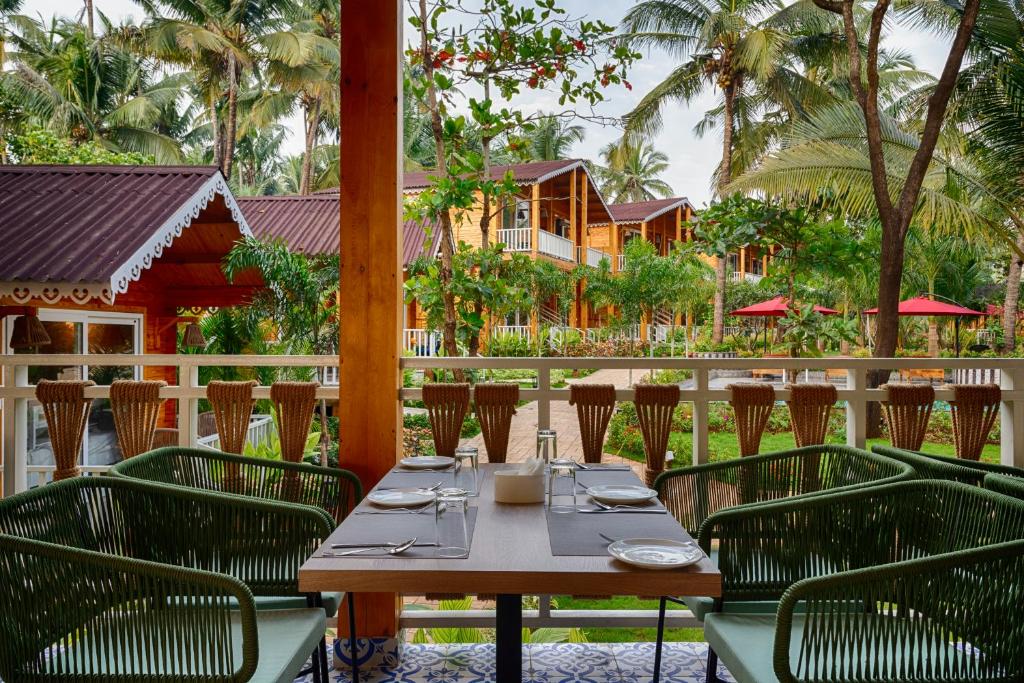 a table and chairs on a patio with a house at Aralea Beach Resort By Stone Wood Premier in Morjim