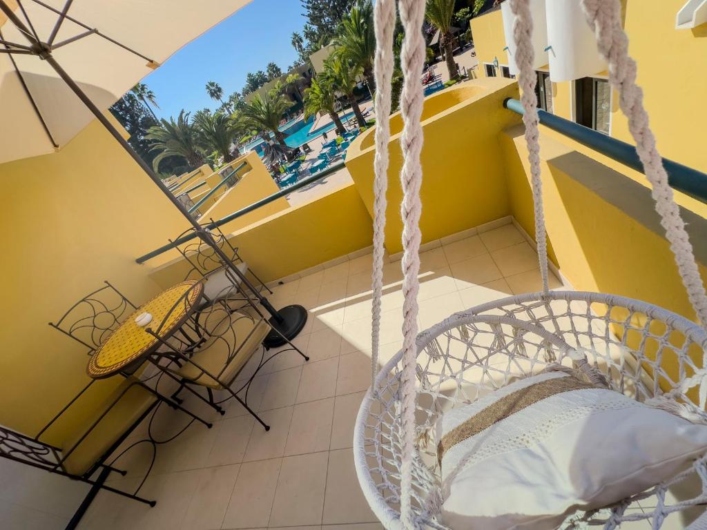 um baloiço numa varanda com vista para a piscina em Villa Rosa Fuerteventura em Corralejo