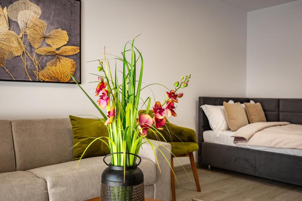 a vase with flowers on a table in a living room at Urban Plaza Alpine Escape Studio with Free Parking, Balcony, Washer & Dryer in Braşov