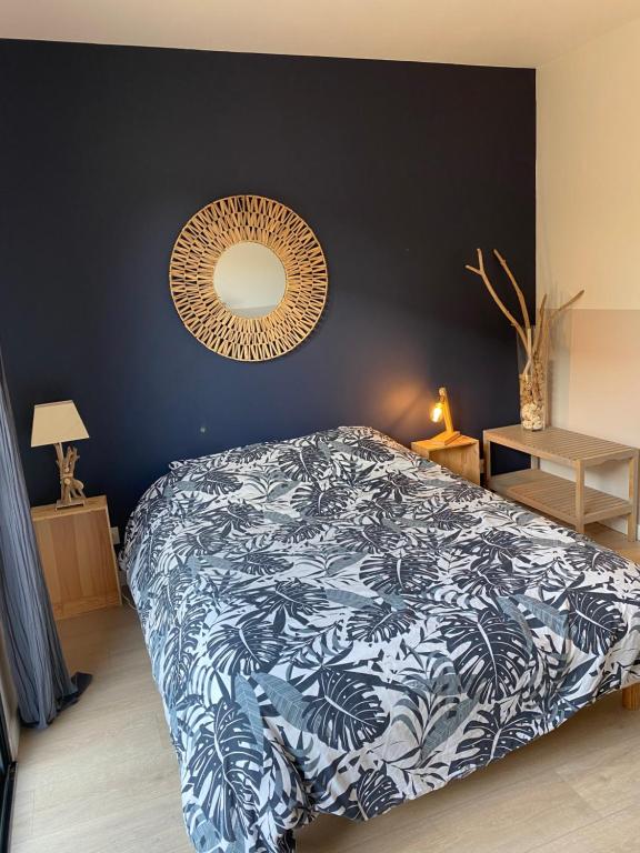 ein Schlafzimmer mit einem Bett mit einer blauen und weißen Decke in der Unterkunft Charmant studio entre bassin et océan in Lège-Cap-Ferret