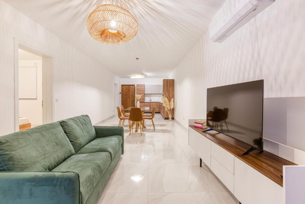 uma sala de estar com um sofá verde e uma televisão de ecrã plano em A beautiful, brand new 2BR home in St Pauls by 360 Estates em St. Paul's Bay
