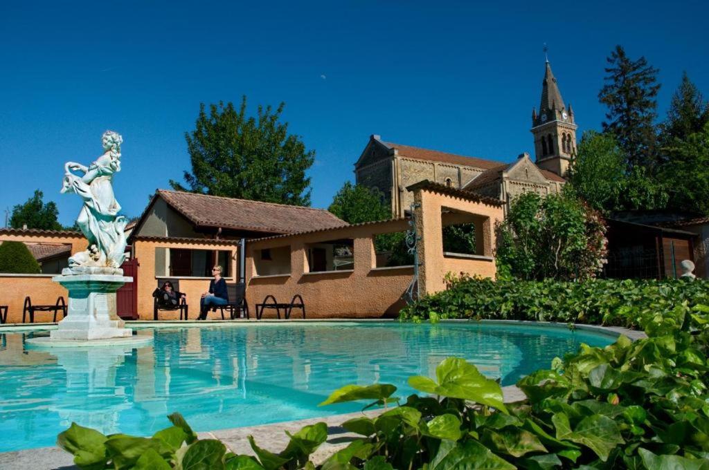 una piscina con una estatua frente a un edificio en Les Jardins du castel gites Annick et Jean paul, en Saint-Georges-dʼEspéranche