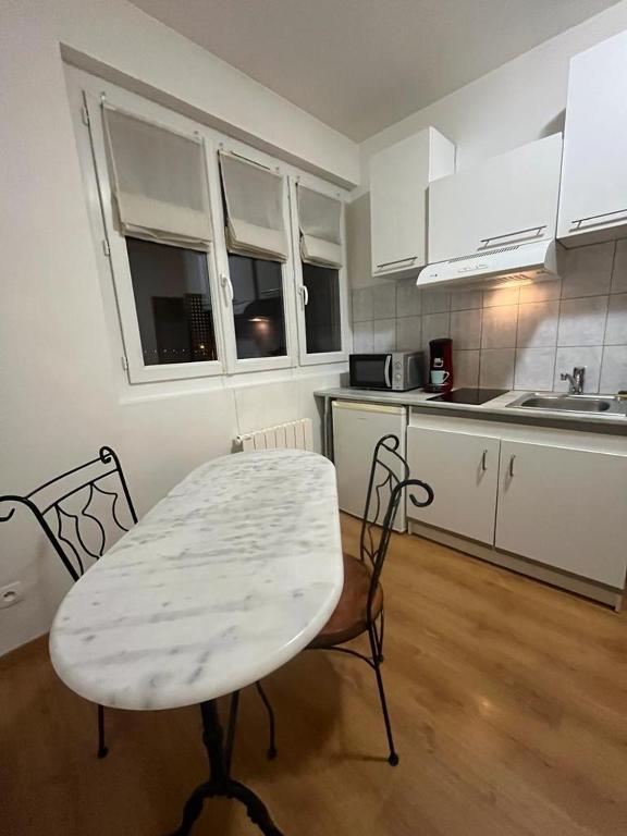 a kitchen with a table and two chairs and a kitchen with white cabinets at Appartement F2 entier près gare RER et SNCF in Conflans-Sainte-Honorine