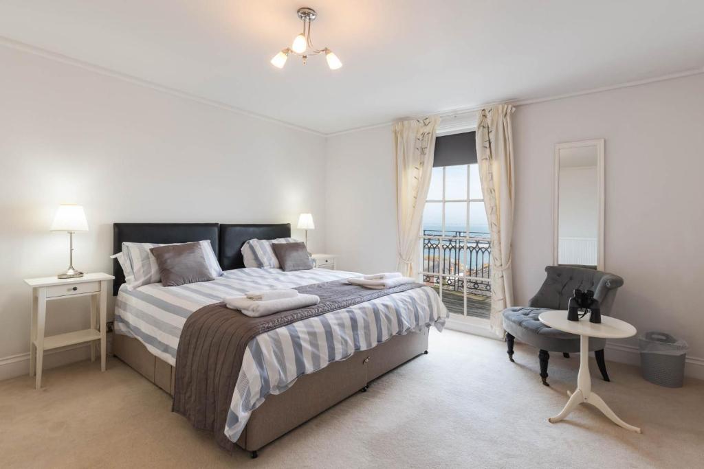 a bedroom with a bed and a table and a window at Cliffhanger 18 Castle Road in Cowes