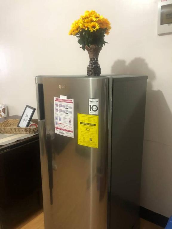 a vase with yellow flowers on top of a refrigerator at Amenadiel & CC - Imus Staycation in Imus