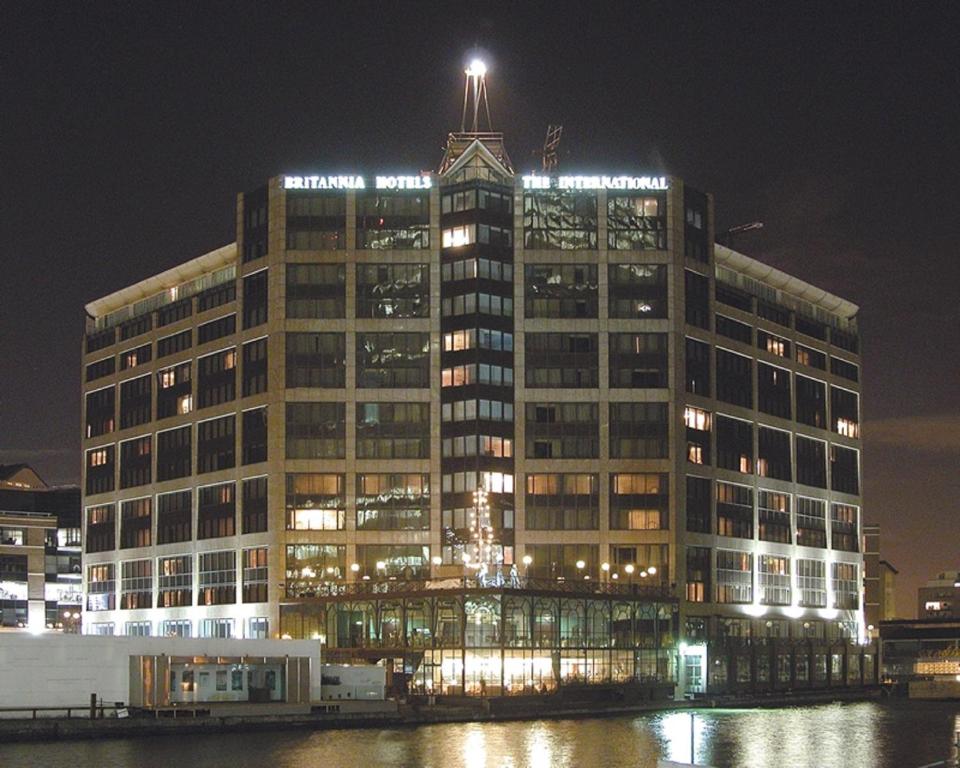 um grande edifício com uma torre de relógio no topo à noite em Britannia International Hotel Canary Wharf em Londres