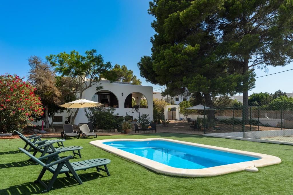 a pool in a yard with two chairs and an umbrella at Ca Nostra Ibiza in Port des Torrent
