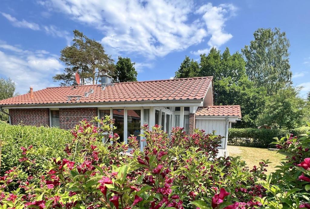 a house with a red roof and some flowers at Mueritz-Ferienhaus-Wiesenblick-|-Garten-Sauna-Kamin-und-Boot-|-200-Meter-zur-Mueritz in Marienfelde