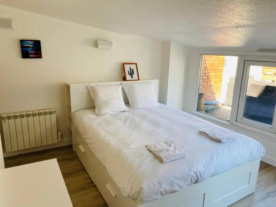 a bedroom with a large white bed with a window at NEW TOP DUPLEX CENTRE AVEC TERRASSE ET PARKING in Clermont-Ferrand