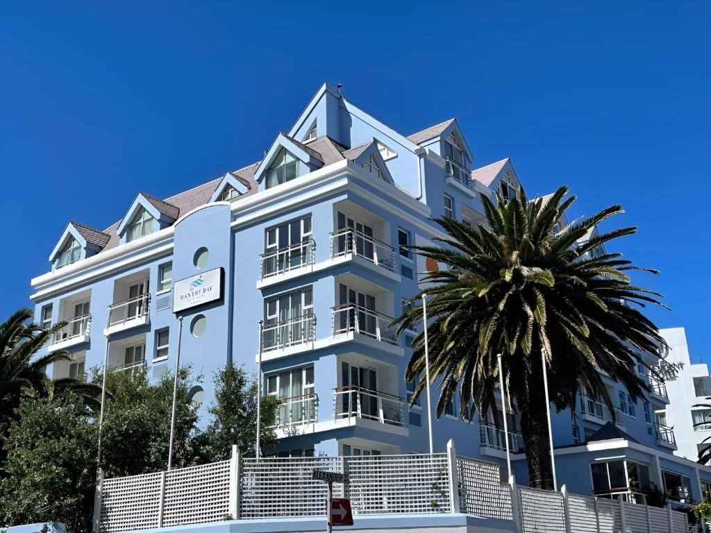 a large white building with a palm tree in front of it at The Bantry Bay Aparthotel by Totalstay in Cape Town