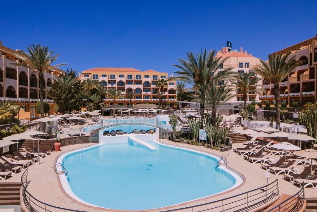 una piscina en un complejo con sillas y sombrillas en Mirador Maspalomas by Dunas, en Maspalomas