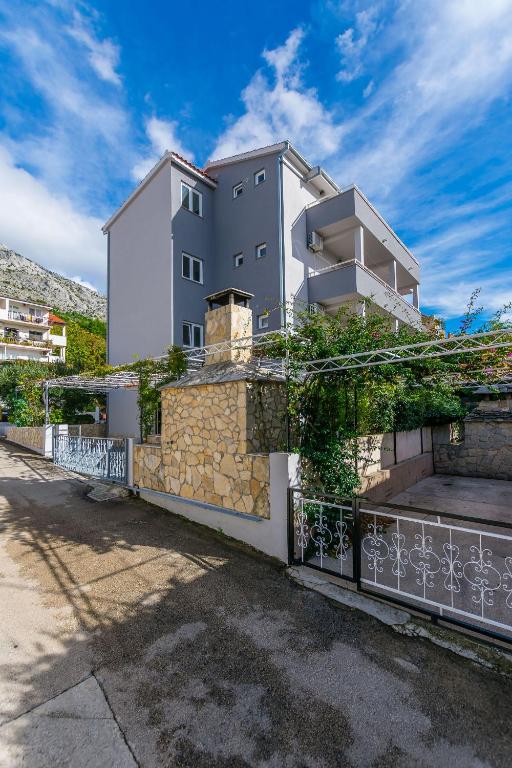 a large white building with a stone wall at Apartment Anica in Omiš