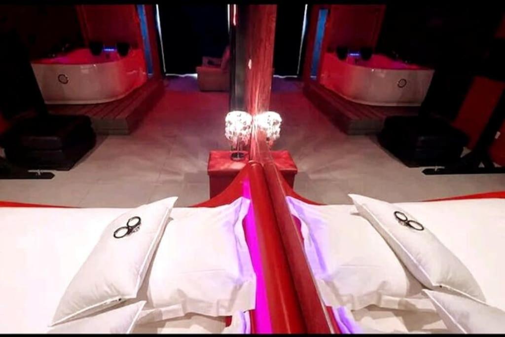 a bed with white pillows on it in a room at Appartement balnéo et sauna privés The Red Room in Mauguio