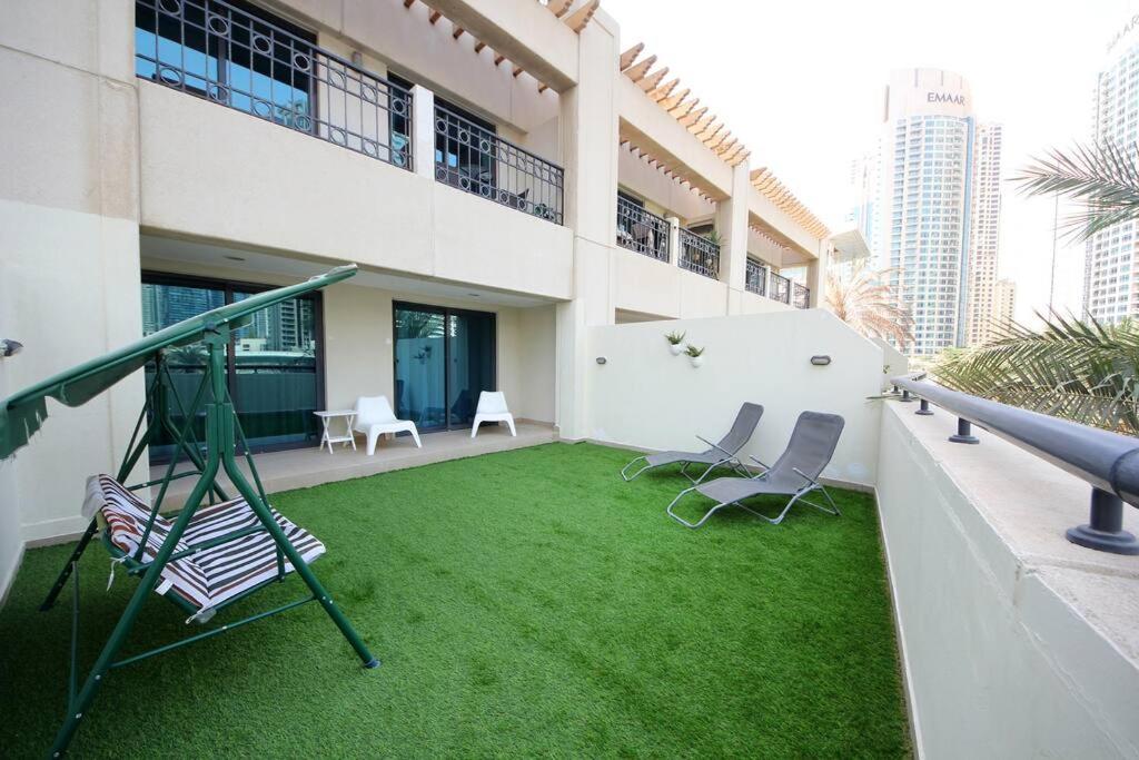 een tuin met een schommel en stoelen in een gebouw bij Skyline Views 1 Bedroom Apartment Lake Facing in Dubai