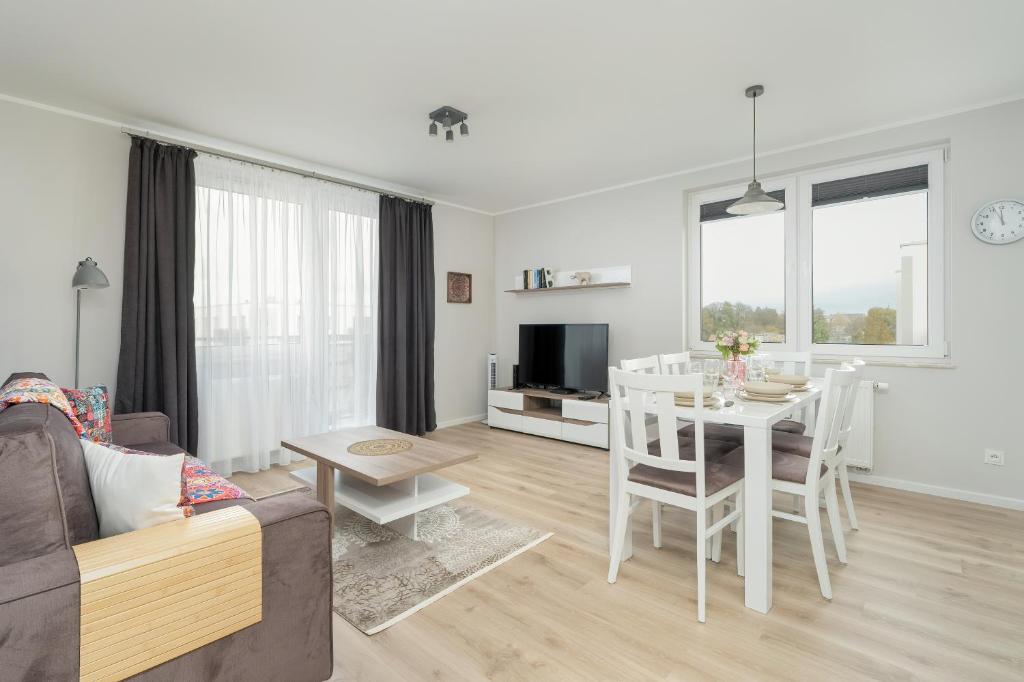 Apartment with 2 Bedrooms and FREE GARAGE Poznań by Renters في بوزنان: غرفة معيشة بيضاء مع طاولة وكراسي بيضاء