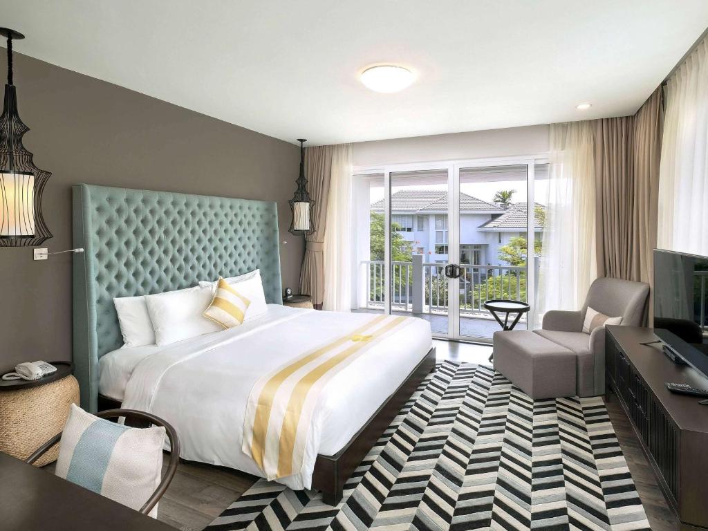um quarto de hotel com uma cama grande e uma televisão em Premier Village Danang Resort Managed By Accor em Da Nang