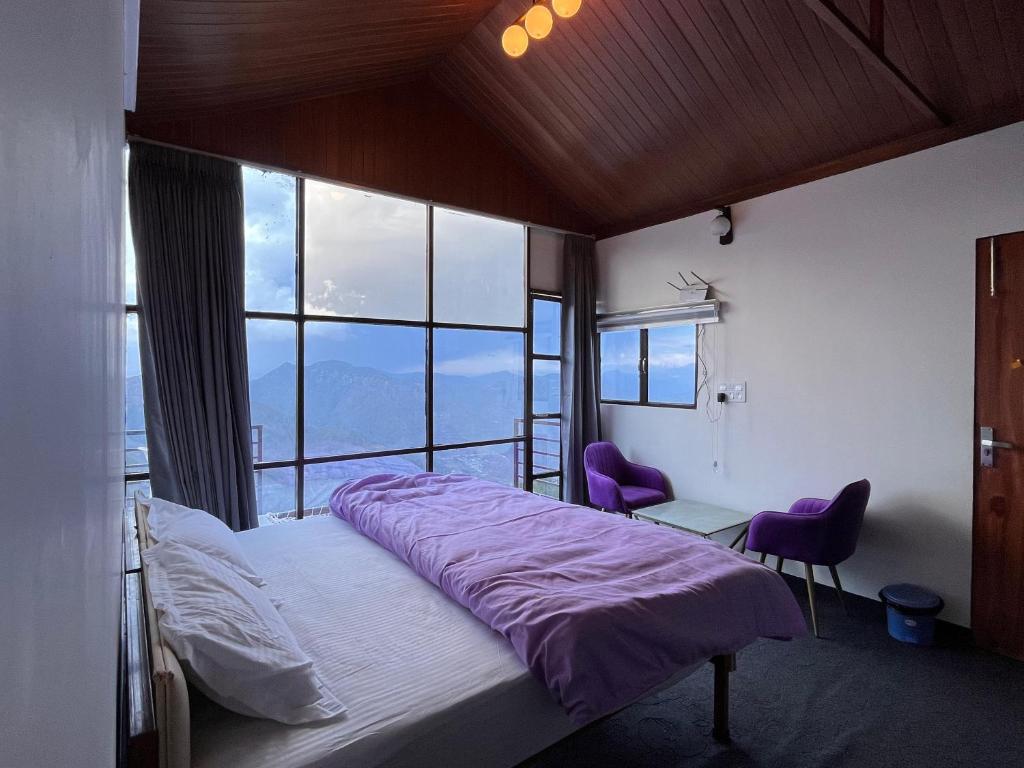 ein Schlafzimmer mit einem Bett und zwei lila Stühlen in der Unterkunft Nivriti Stays in Kanatal