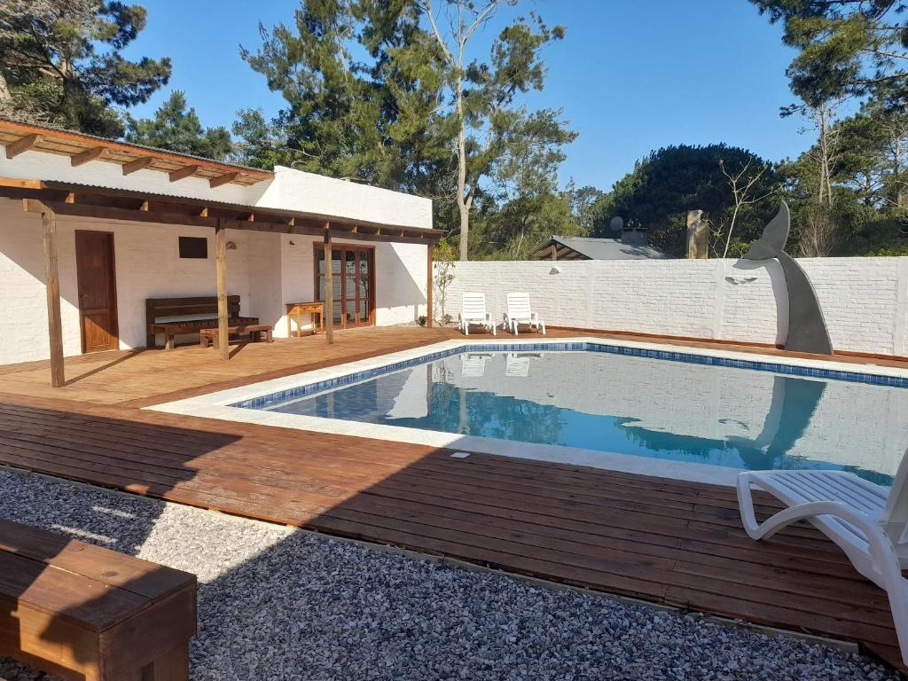 a swimming pool with a wooden deck next to a house at Posada Yaguane in La Paloma