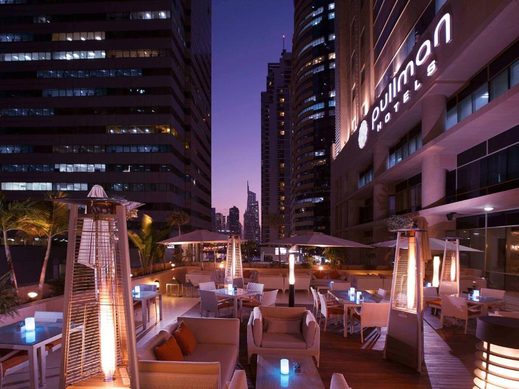 a rooftop patio with tables and chairs and buildings at Pullman Dubai Jumeirah Lakes Towers in Dubai