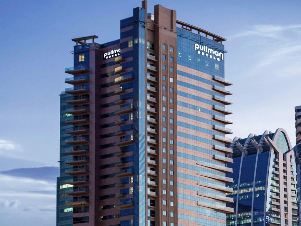 un edificio alto con un cartel en el costado en Pullman Dubai Jumeirah Lakes Towers en Dubái