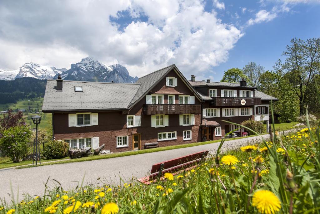 ein großes Haus auf einer Straße mit Bergen im Hintergrund in der Unterkunft Schwendi Lodge in Unterwasser