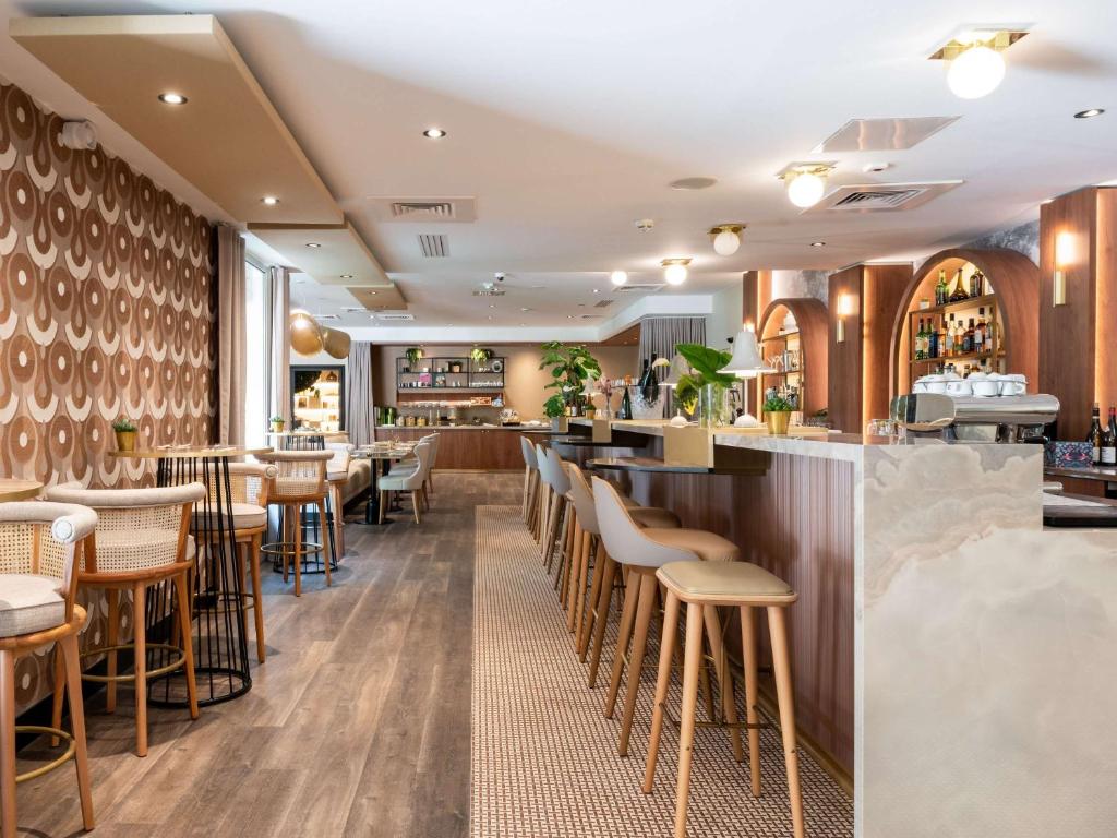 un restaurant avec des tabourets en bois et un bar dans l'établissement Mercure Paris Ouest Saint Germain, à Saint-Germain-en-Laye