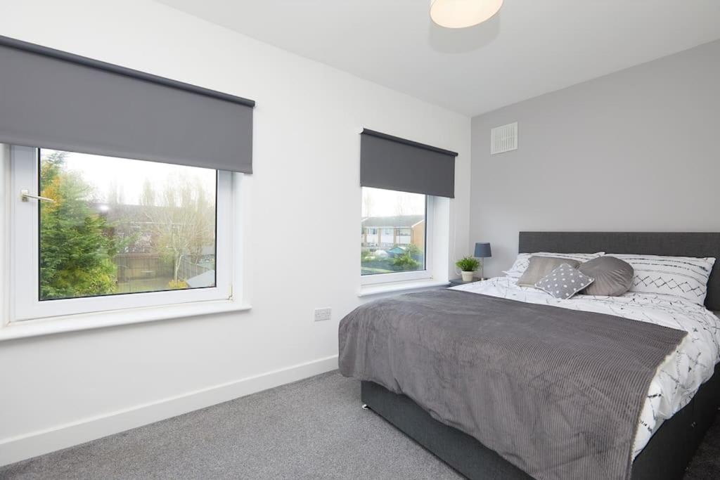 a white bedroom with a bed and two windows at 2 Bed Littleover Derby House (long stays / parking) in Derby