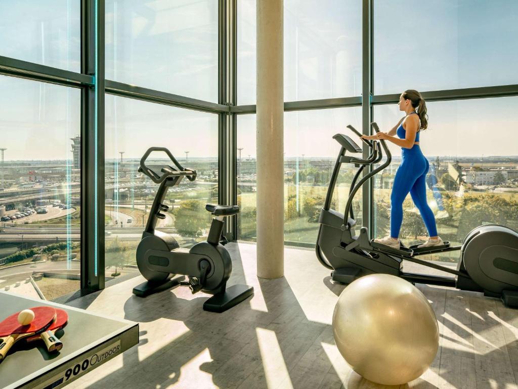 a woman running on a treadmill in a gym at Novotel Paris Coeur d'Orly Airport in Orly