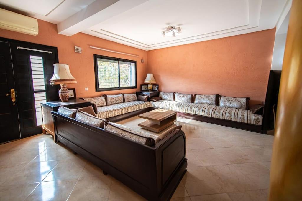 una gran sala de estar con sofás y una mesa. en Belle villa spacieuse et cosy, en Marrakech