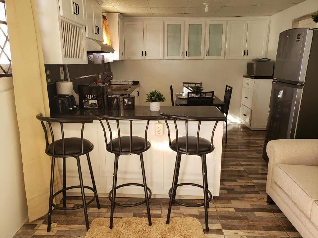 a kitchen with a counter and stools in a room at Mango Vert Apartment in Arima