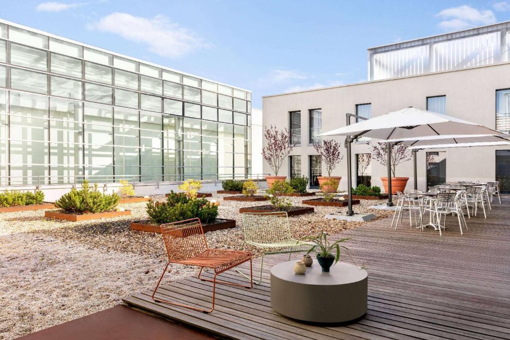 eine Terrasse mit Stühlen und Tischen sowie ein Gebäude in der Unterkunft Vienna House Easy by Wyndham Stuttgart in Stuttgart