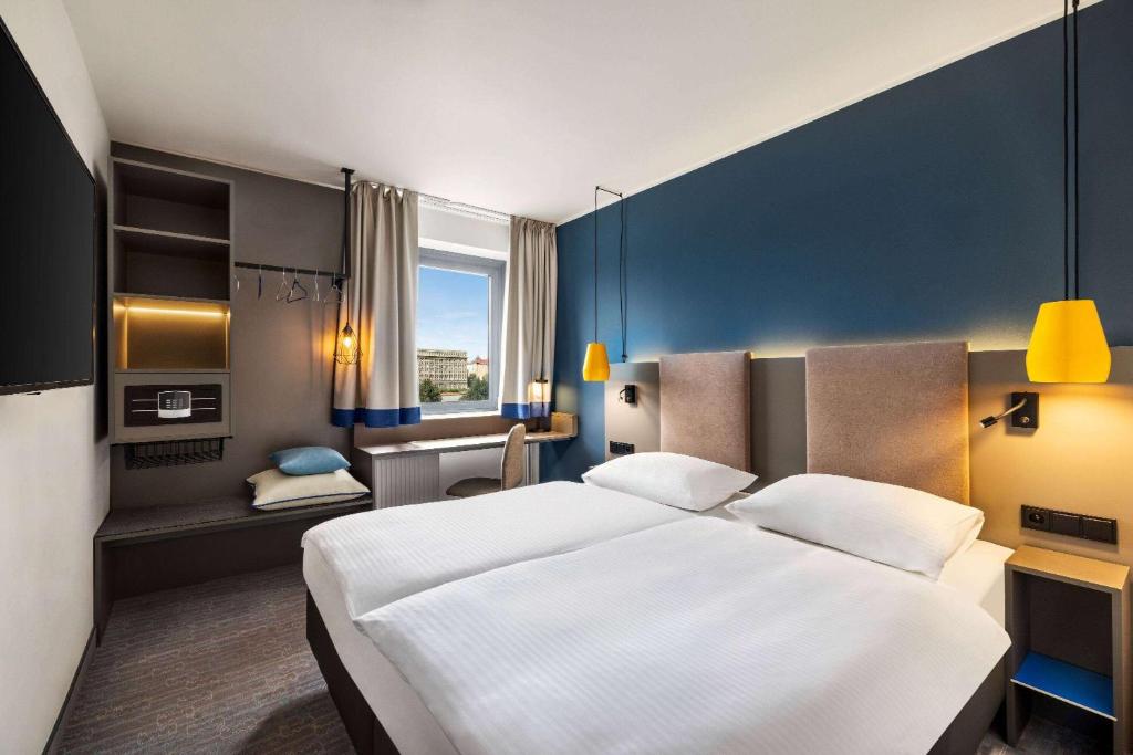 a hotel room with a large bed and a desk at Vienna House Easy by Wyndham Cracow in Krakow