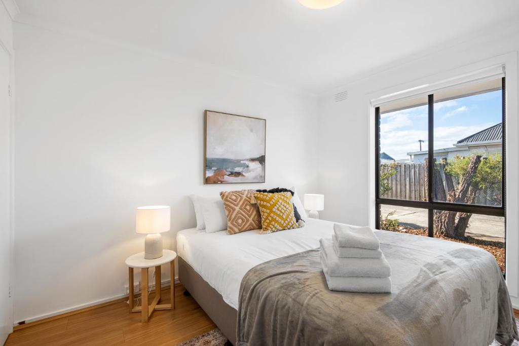 ein weißes Schlafzimmer mit einem Bett und einem Fenster in der Unterkunft Wilson Executive Apartments in Thomson