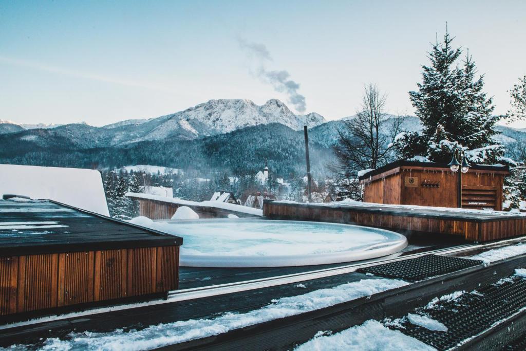 a hot tub on a snow covered roof with mountains at Tatra Resort & SPA in Kościelisko