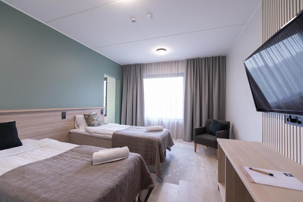 a hotel room with two beds and a flat screen tv at Kisakallion Urheiluopisto, Lohja in Lohja