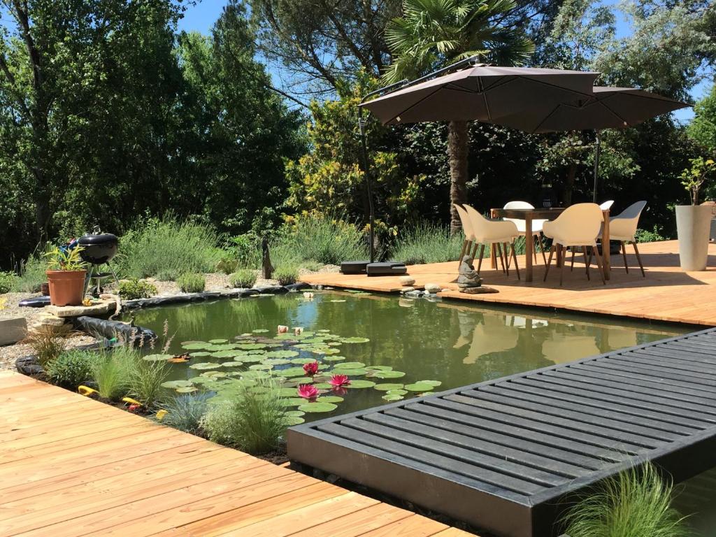 a pond with an umbrella and a table and chairs at L'eau douce in Gasques