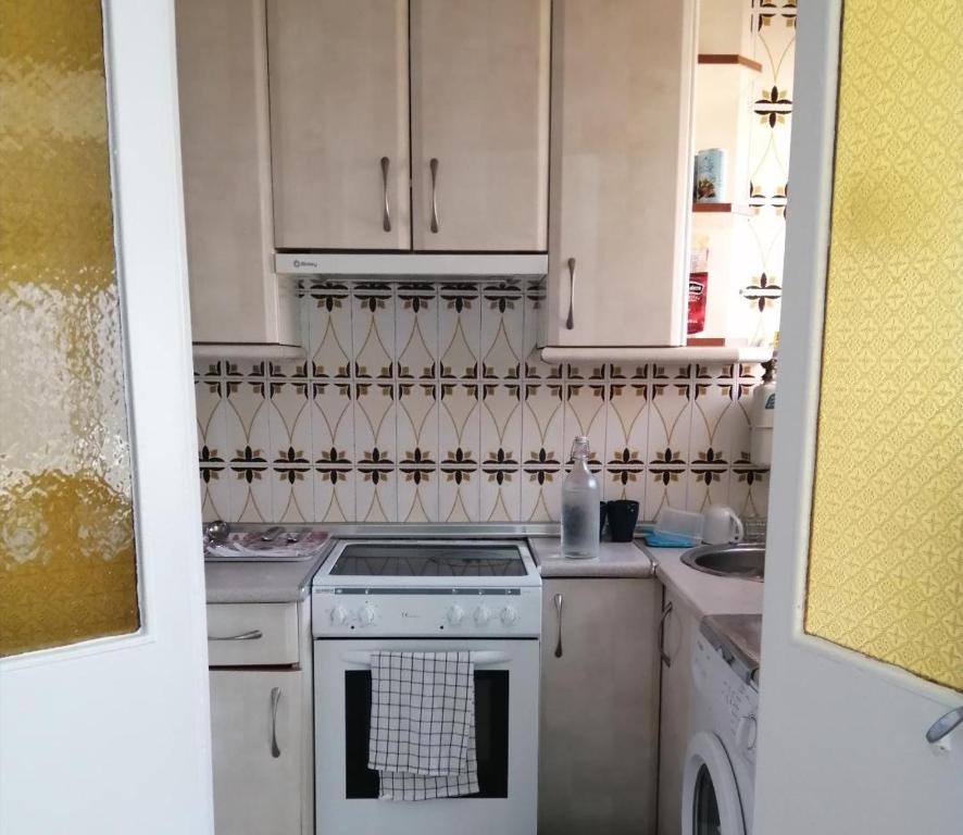 uma cozinha com armários brancos e um forno com placa de fogão em La Pequeña Cercona em La Granja de San Ildefonso