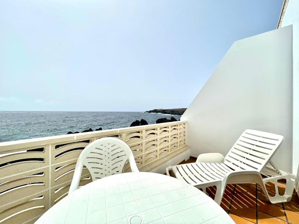 Un balcón con sillas, una mesa y el océano en Apartamento de 1 dormitorio frente al mar en Tamaduste, en Tamaduste